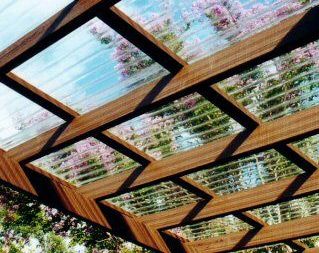 a wooden pergoline covered in flowers next to trees