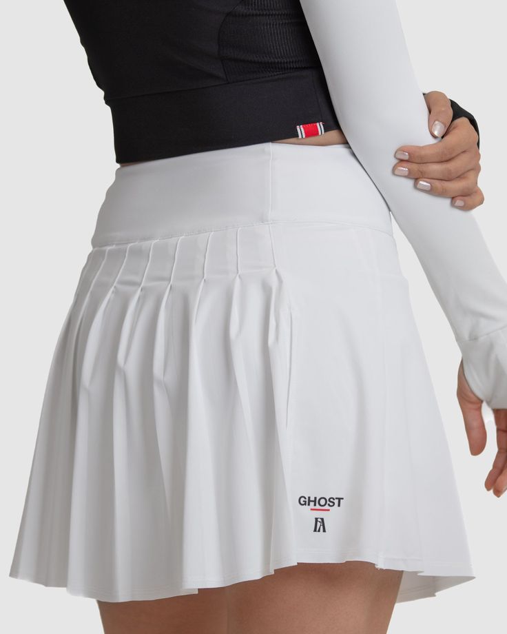 Introducing the Anika Golf Skirt, designed for a stylish and comfortable appearance on the course. Featuring built-in compression shorts with soft silicone grips, it ensures stability during swings. With its flattering silhouette and playful design, this skirt instills confidence for powerful shots. Elevate your golf wardrobe with the Anika Golf Skirt, a perfect blend of style and functionality. Fit: High-waisted design, sitting just above the belly button for a flattering silhouette. Featuring a 3 ¾” waistband with built-in tummy control for added comfort and support. Subtle A-line silhouette offers a stylish and versatile look. Front length measures 17 inches, providing ample coverage. Soft curve up at the side seam, starting at 15 ½” and gently curving back down to 17” at the back, ensu White 4-way Stretch Skirt With Built-in Shorts, White Fitted Mini Skort, Fitted White Mini Skort, Athleisure Mini Tennis Skirt For Cheerleading, Cheerleading Tennis Skirt In Athleisure Style, White Lined Skort For Athleisure, White Mini Tennis Skirt For Sports, Sporty Mini Length Lined Tennis Skirt, Sporty Mini Length Tennis Skirt With Lining