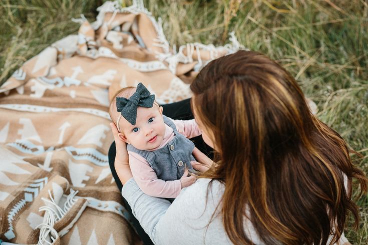 a woman holding a baby on top of a blanket