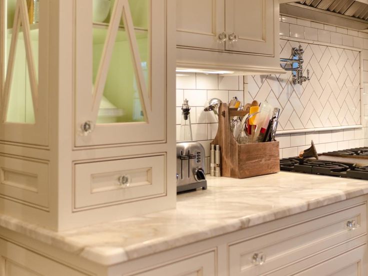 a kitchen with white cabinets and marble counter tops is pictured in this image, there are utensils hanging on the cabinet doors