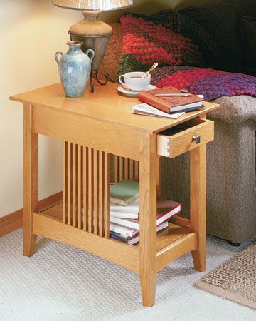 a coffee table with books and a vase on it in front of a couch next to a lamp