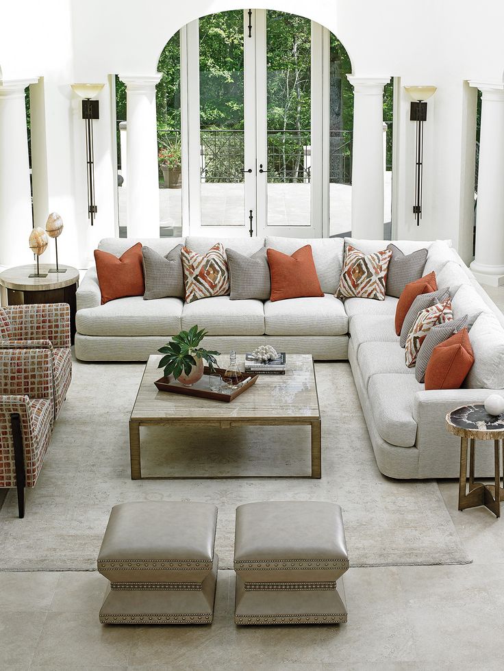 a living room with couches, chairs and tables in front of two large windows