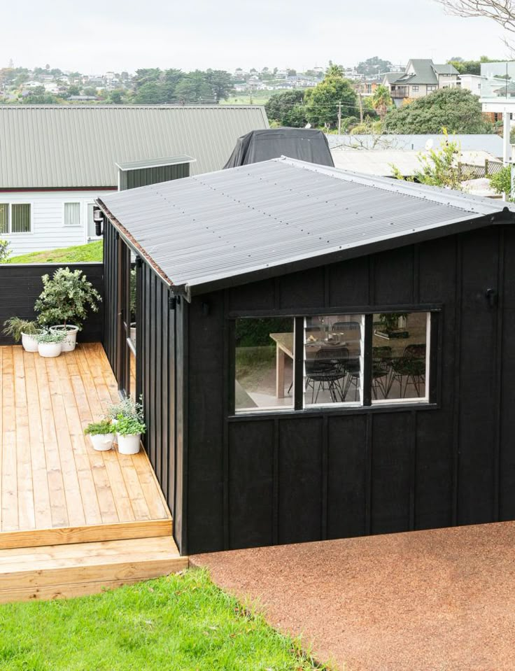 a small black shed sitting on top of a wooden deck