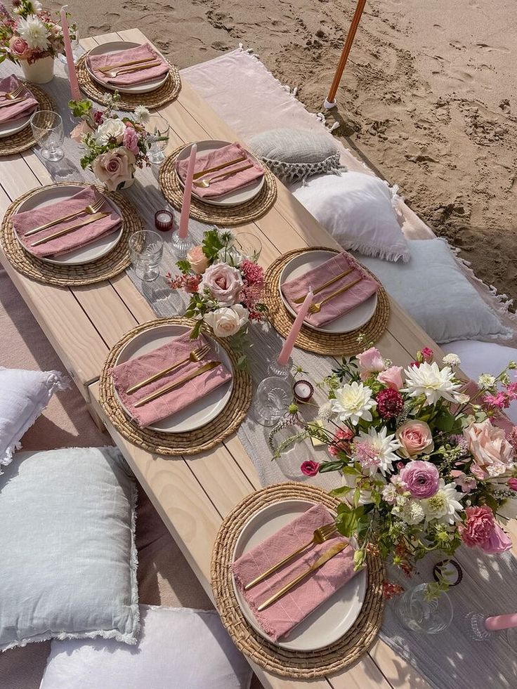 a table set up with pink and white plates, napkins and flowers on it