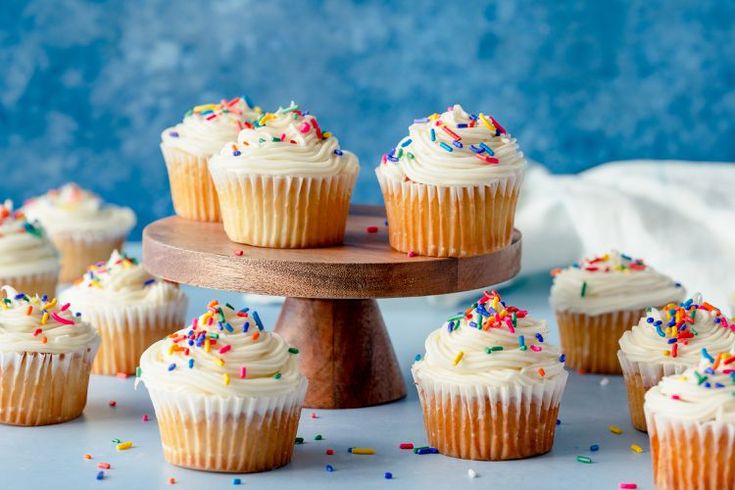 cupcakes with white frosting and sprinkles on a cake stand