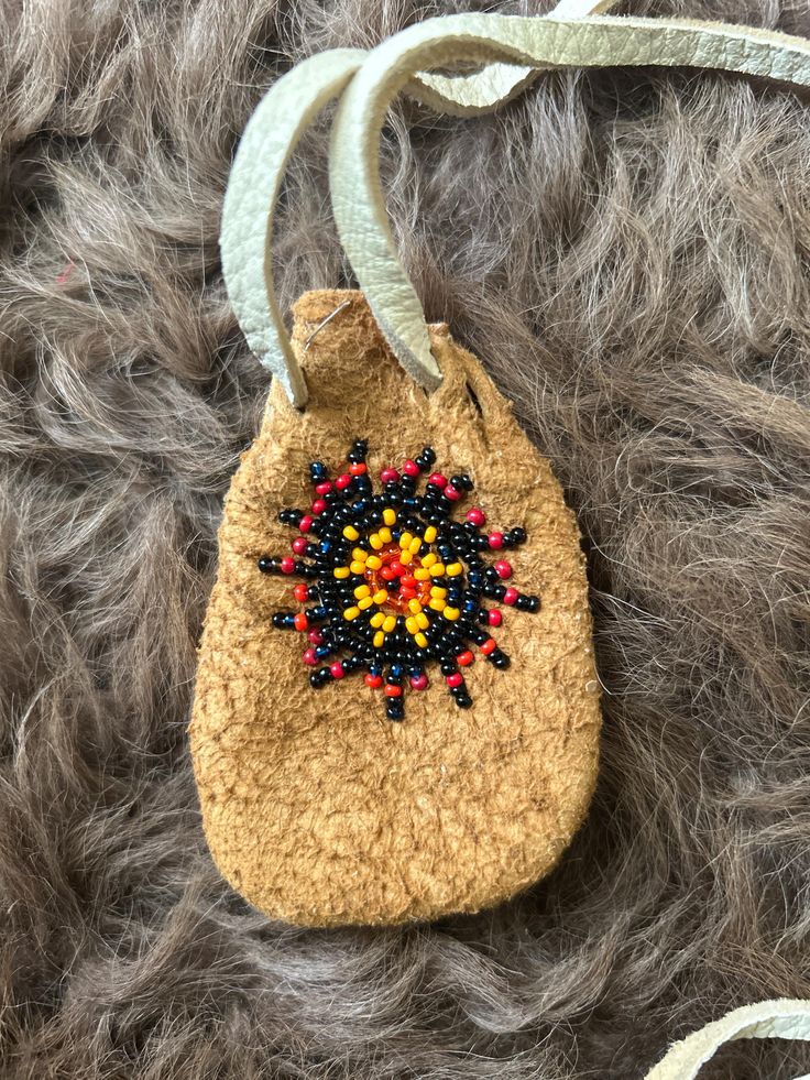 a small bag with beads hanging from it's side on top of some fur