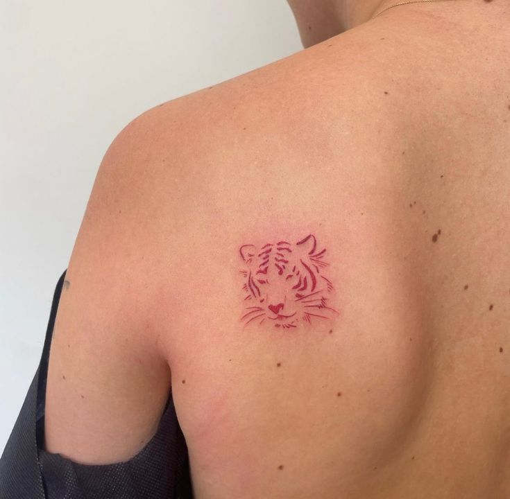 a close up of a person with a tattoo on their back and shoulder, showing the tiger's head