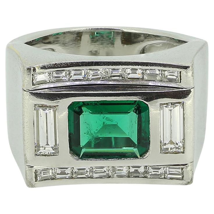 Here we have a substantial yet stylish emerald and diamond ring. A square platinum head plays host to a rich transparent green emerald cut emerald at the centre of the face. This principal stone is flanked on either side by a single straight baguette cut diamond in a vertical formation. This trio sits slightly risen at the centre of the face amidst a single row of matching smaller baguette cut diamonds above and below. The piece is then made complete by wide unembellished shoulders and matching plain shank. Condition: Used (Very Good) Weight: 17.5 grams Size: O (55) Band Width: 14mm - 6mm Emerald Weight: Approx. 1.41ct Emerald Details: Origin: Zambia Treatment: Minor Oil Grading Laboratory: The Gem & Pearl Laboratory Total Diamond Carat Weight: Approx. 0.70ct Diamond Details: Colour: G-H, Vintage Emerald Rings 1stdibs, Emerald Ring 1stdibs, Luxury Multi-stone Emerald Ring Collectible, Luxury Square-cut Emerald Ring Fine Jewelry, Luxury Collectible Emerald Cabochon Ring, Emerald Diamond Ring, La Face, Baguette Cut Diamond, Zambia