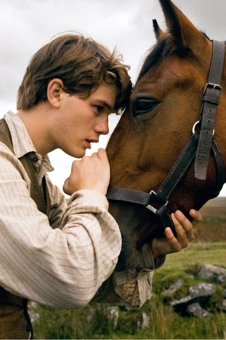 a man standing next to a brown horse