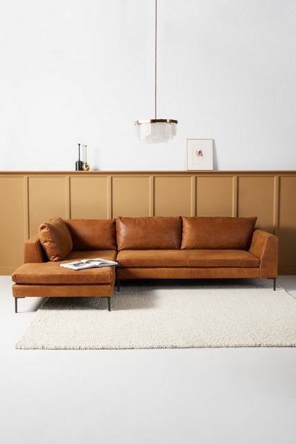 a brown leather couch sitting on top of a white rug