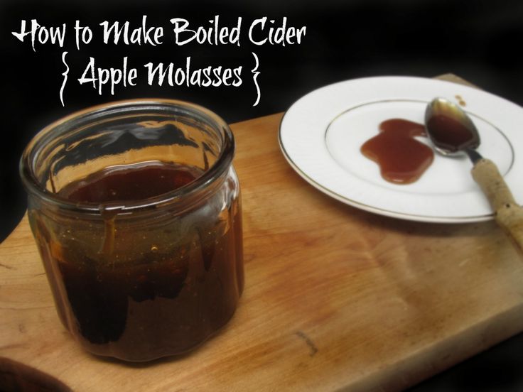 a jar of apple cider sitting on top of a wooden cutting board next to a white plate