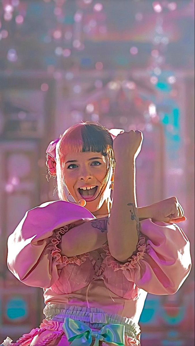 a woman in a pink top is dancing with her arms up and hands behind her head