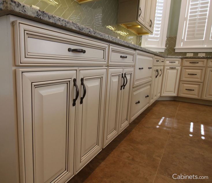 a large kitchen with white cabinets and marble counter tops, along with hardwood flooring