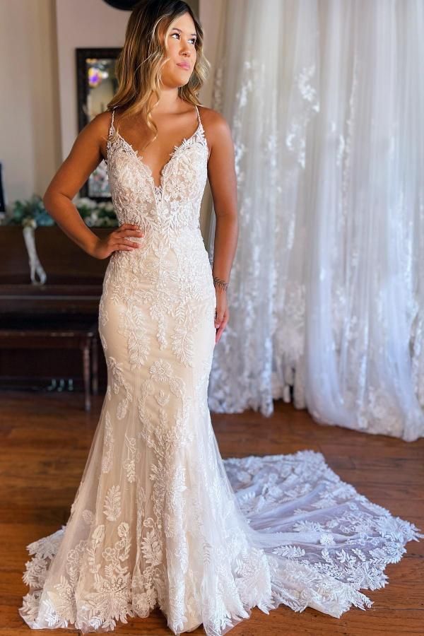 a woman in a wedding dress standing on a wooden floor with her hands on her hips