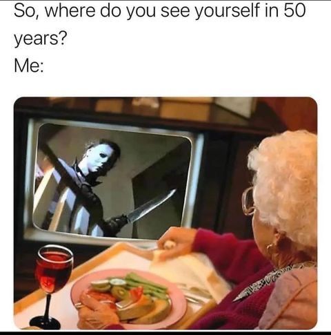 an old woman sitting at a table in front of a tv with the caption so, where do you see yourself in 50 years? me