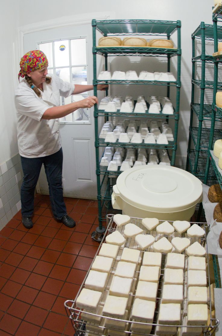 a woman standing in front of some shelves filled with cakes and pastries on display