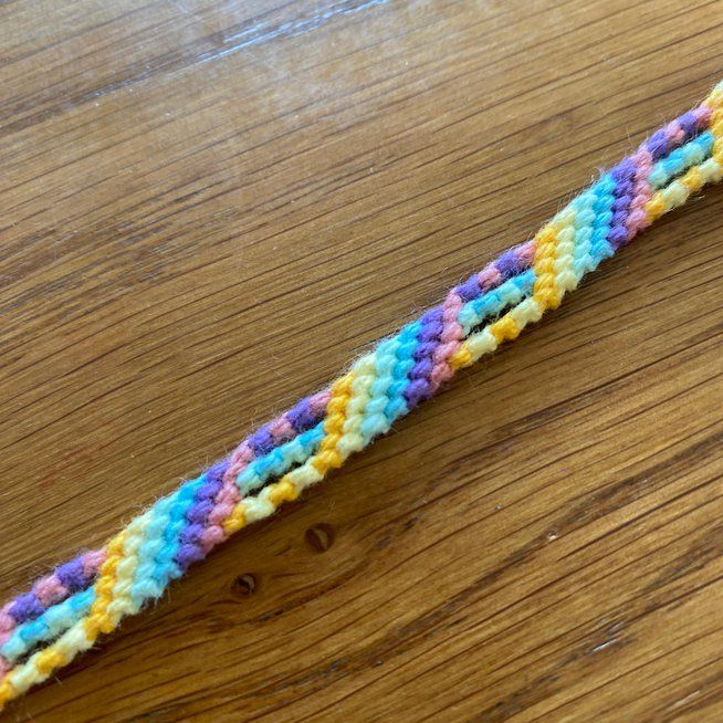 there is a multicolored crochet bracelet on the table