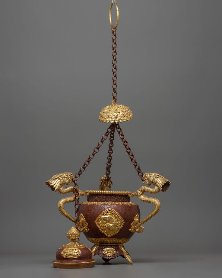 an ornately decorated vase with chains hanging from it's sides and two smaller bowls on either side