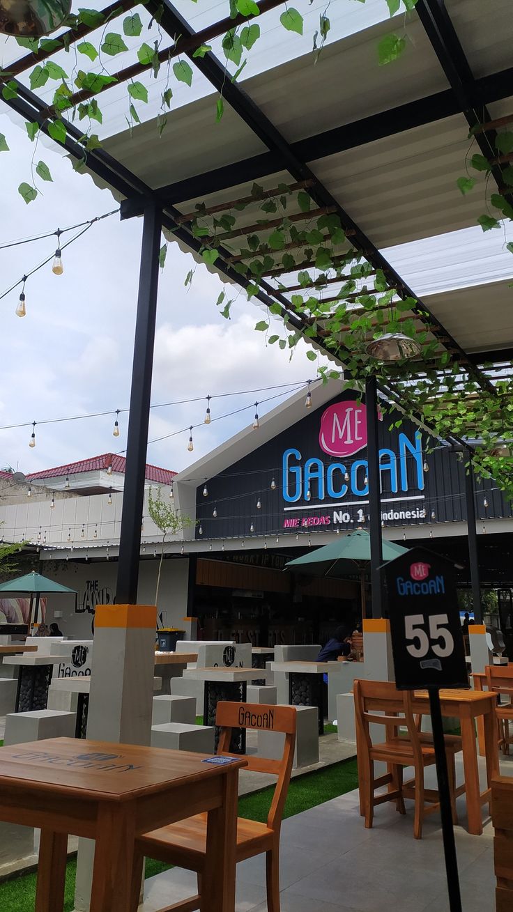 an outdoor restaurant with tables and chairs under a canopy over the outside seating area for people to sit at