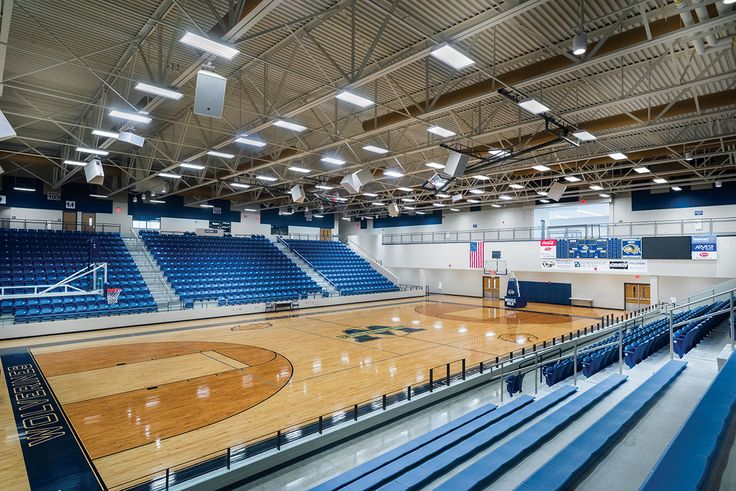 an empty basketball court with blue seats and lights on the sidelines is seen in this image