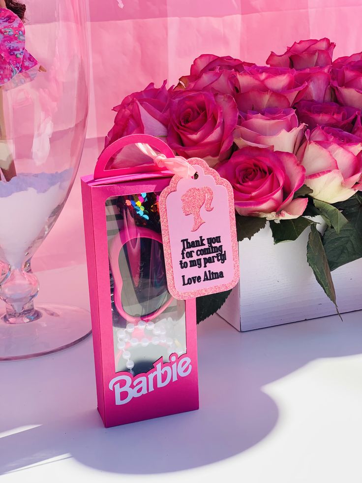 pink roses are in a vase next to an empty barbie sunglasses and a card holder