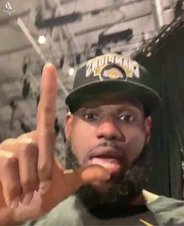 a man with a beard and hat making the peace sign while standing in front of a brick wall