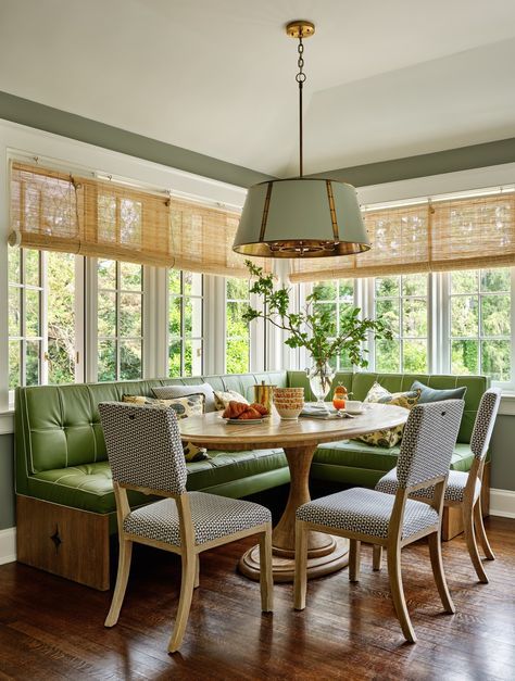 a dinning room table with four chairs and a bench in front of the window