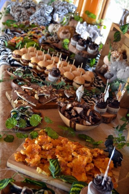 a table filled with lots of food on top of wooden trays covered in greenery