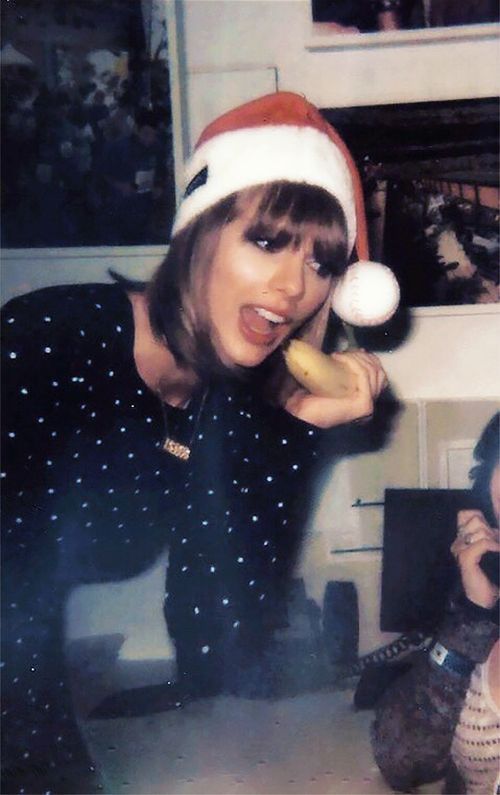 a woman in a santa hat holding a banana up to her face while another woman looks on