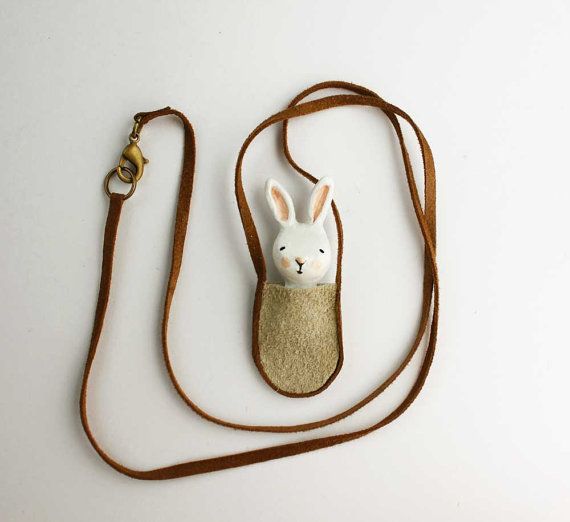 a small white rabbit in a pouch on a brown cord with a keychain