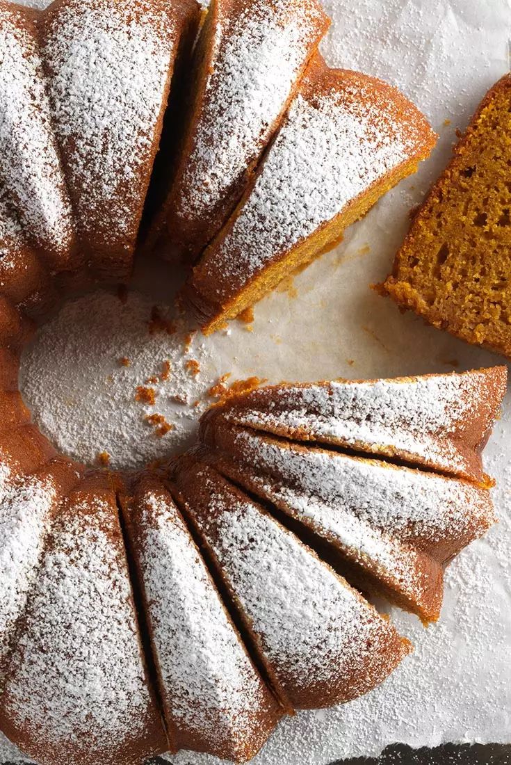 a bundt cake with powdered sugar on top next to a piece of bread