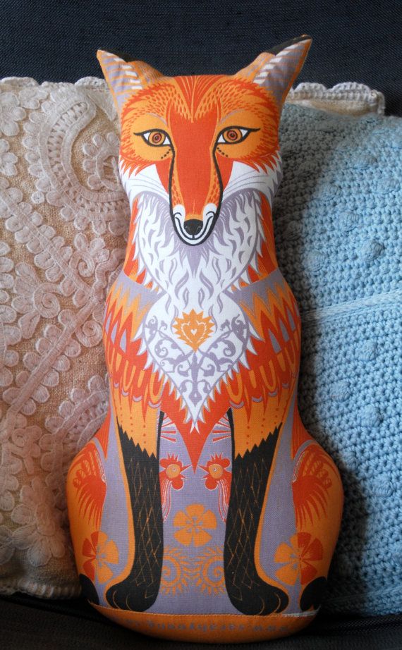 an orange fox sitting on top of a pillow