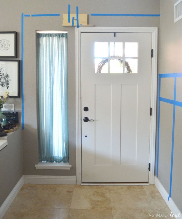 a white door with blue tape on it in a room that is painted light gray