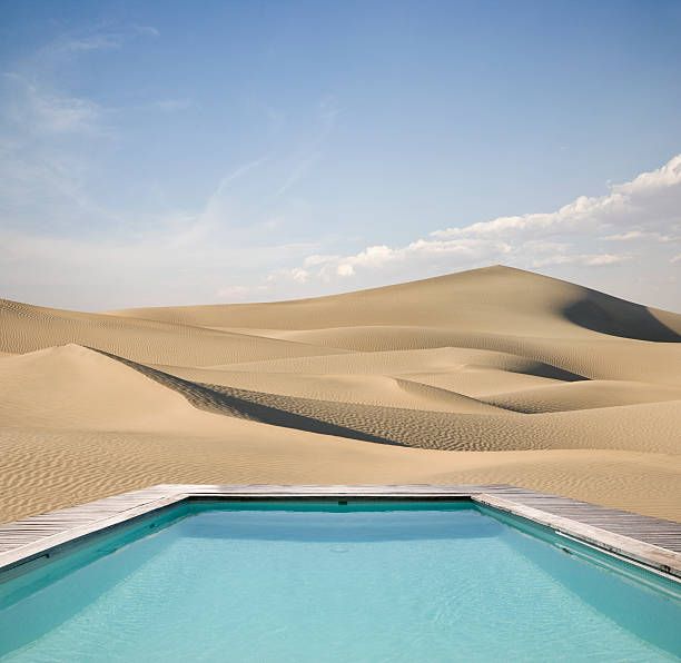 a swimming pool in the middle of sand dunes