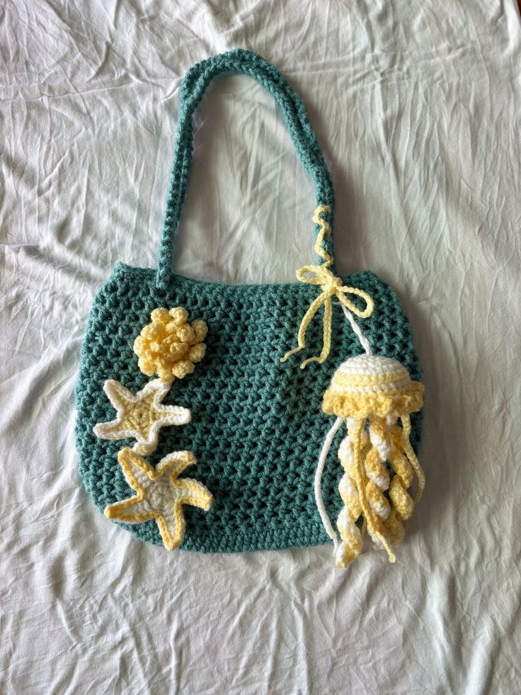 a crocheted bag with jellyfish and starfish decorations on it's handles