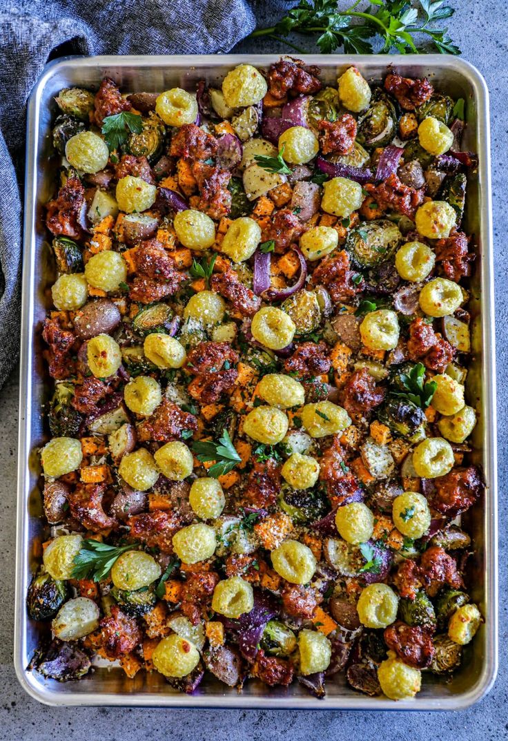 a casserole dish with roasted vegetables and herbs on the side, ready to be eaten