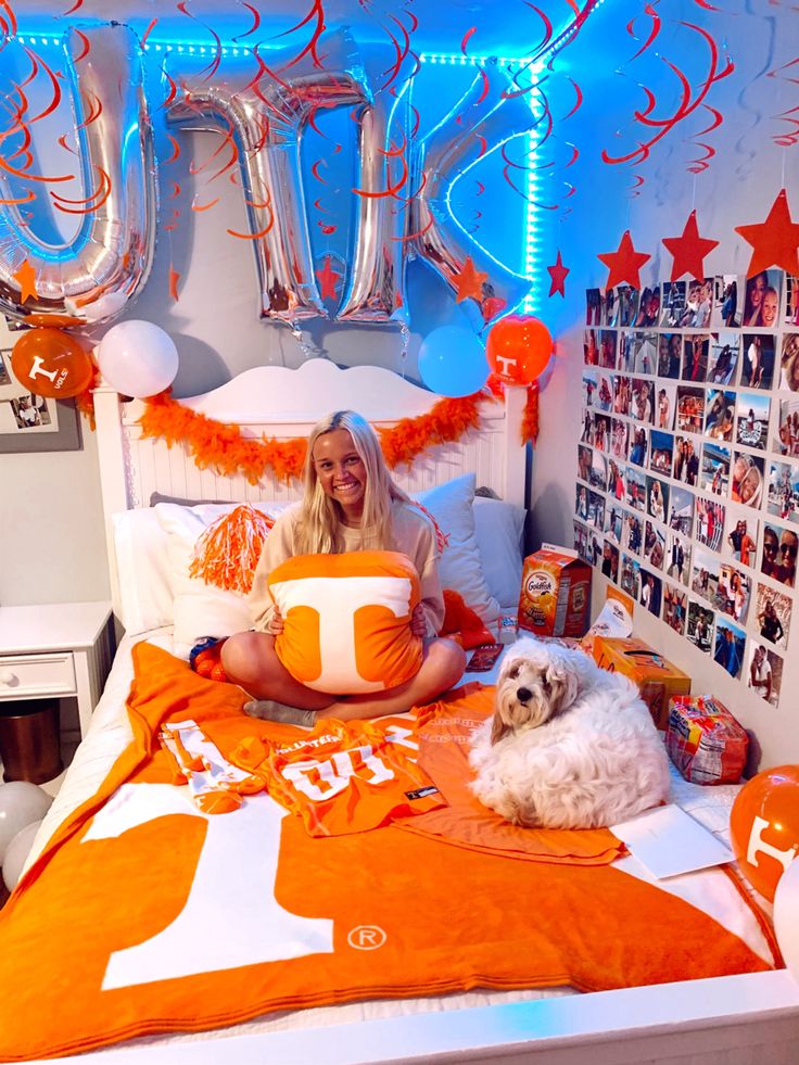 a woman laying in bed with her dog and balloon decorations on the wall behind her