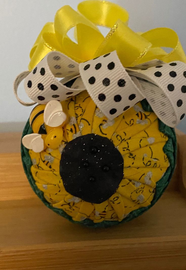 a yellow and black flower with polka dots on it's head is sitting on a wooden table