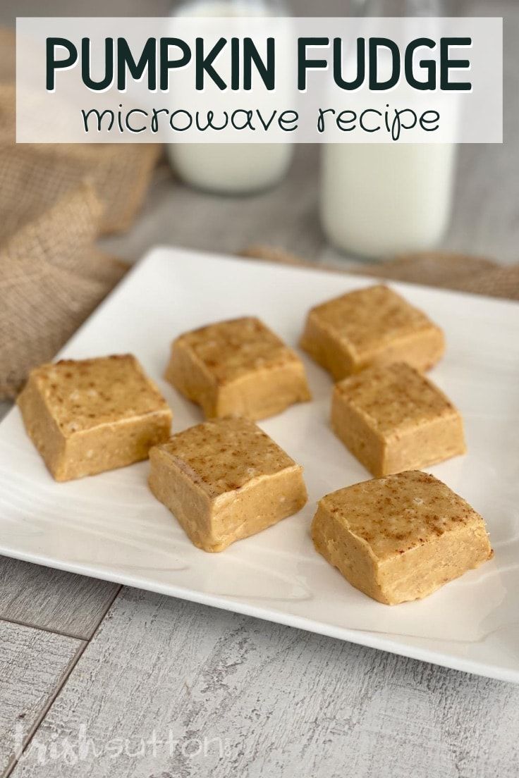 four pieces of pumpkin fudge on a white plate next to a glass of milk