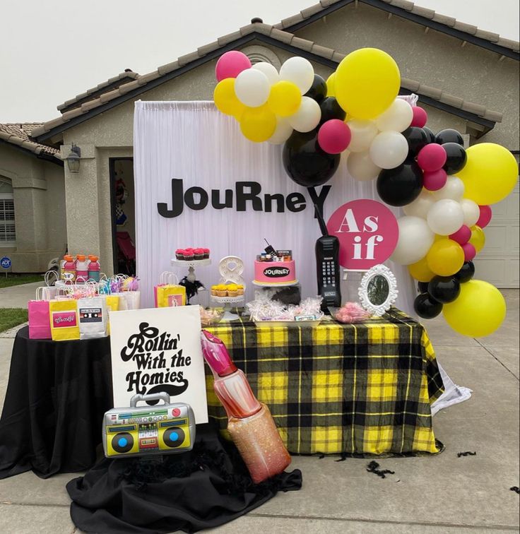 a table topped with balloons and other items in front of a sign that says journey