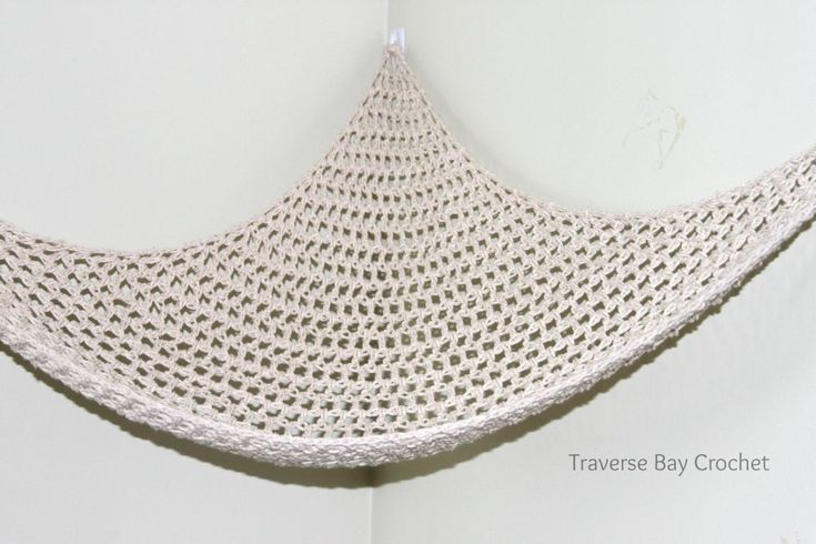 a white crocheted hammock hanging from a hook on the wall in a room