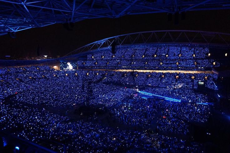 an arena full of people at a concert with blue lights on the ceiling and in the stands