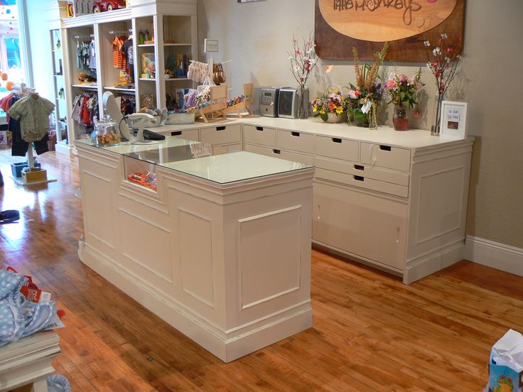 a room filled with lots of white furniture and decor on top of hard wood floors