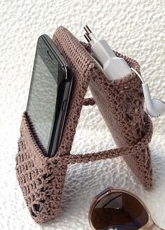 a crocheted cell phone case sitting next to a pair of sunglasses