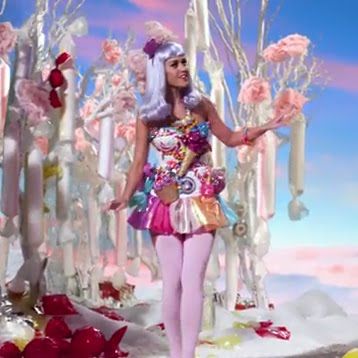 a woman dressed in pink and white standing next to some trees with flowers on them