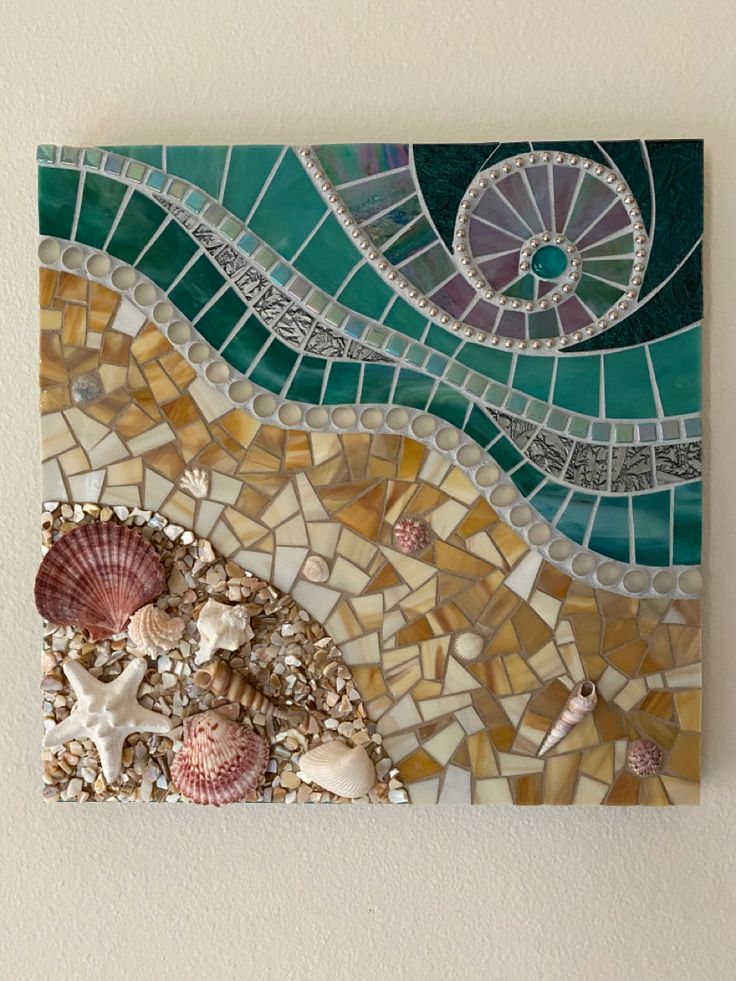 a piece of art with shells and sea glass on the bottom, in front of a white wall