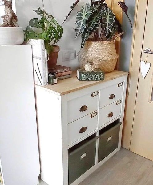 a white cabinet with drawers and plants on top