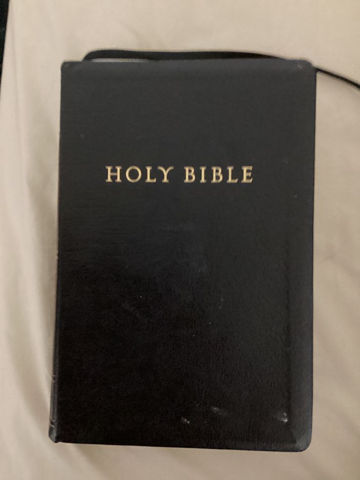 a black bible sitting on top of a bed