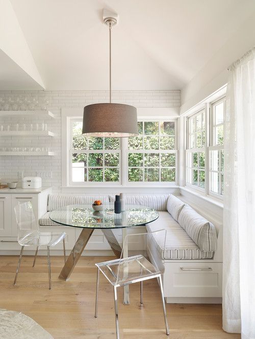 a white room with a glass table and bench next to a window in the corner