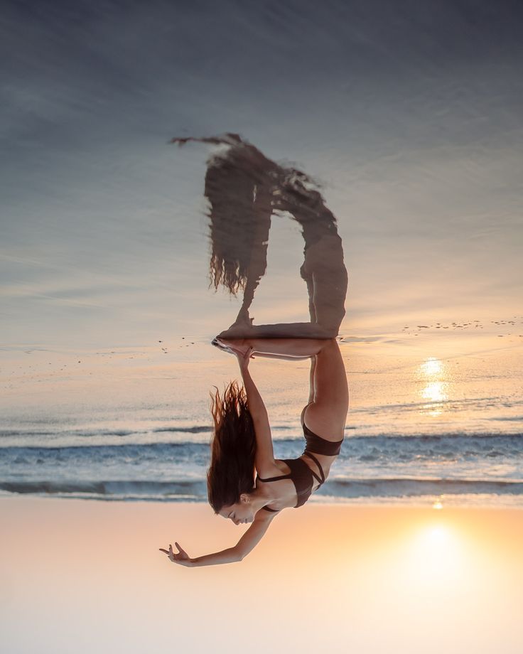 a woman is doing a handstand on the beach